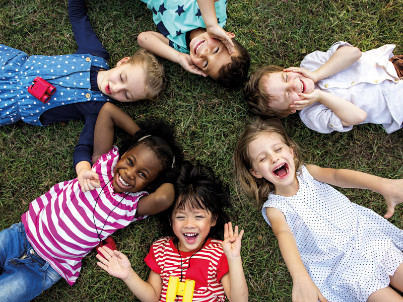 Kinder liegen im Kreis auf Wiese