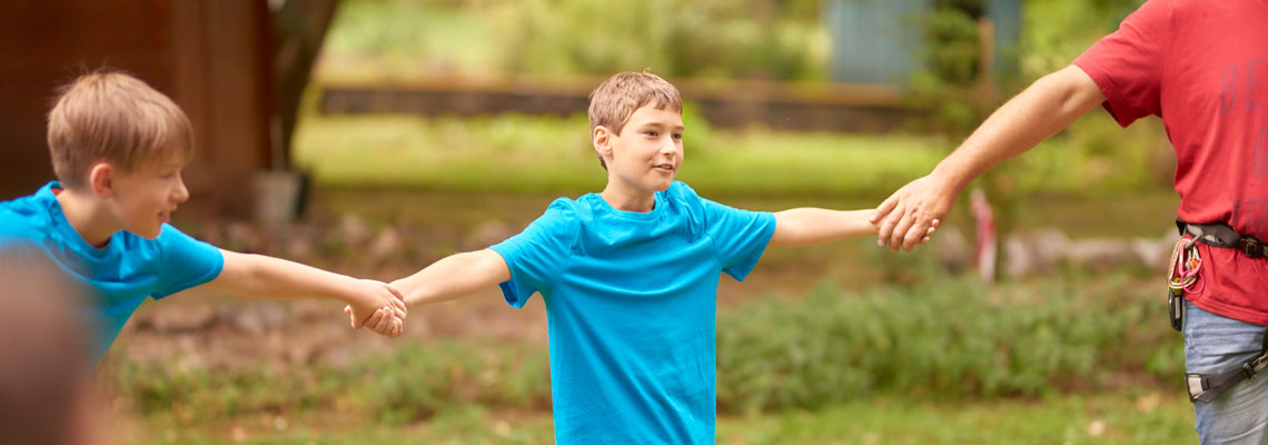 Kinder bilden eine Kette, Spiele draußen in einer Tagesgruppe der Kinder-, Jugend- und Familienhilfe Stiftung kreuznacher diakonie