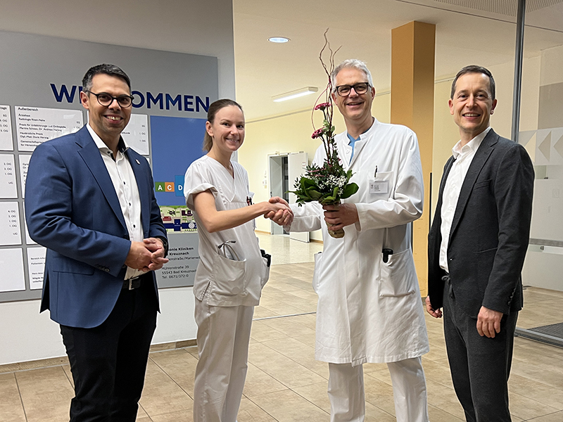 Chefarzt und Klinikleitung gratulieren mit Blumen Assistenzärztin zum Weltmeistertitel im Triathlon 