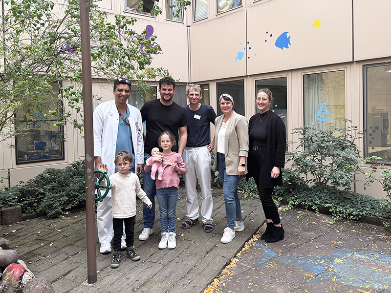 Gruppenbild mit Familie und Mitarbeitenden des Krankenhauses auf dem Spielplatz