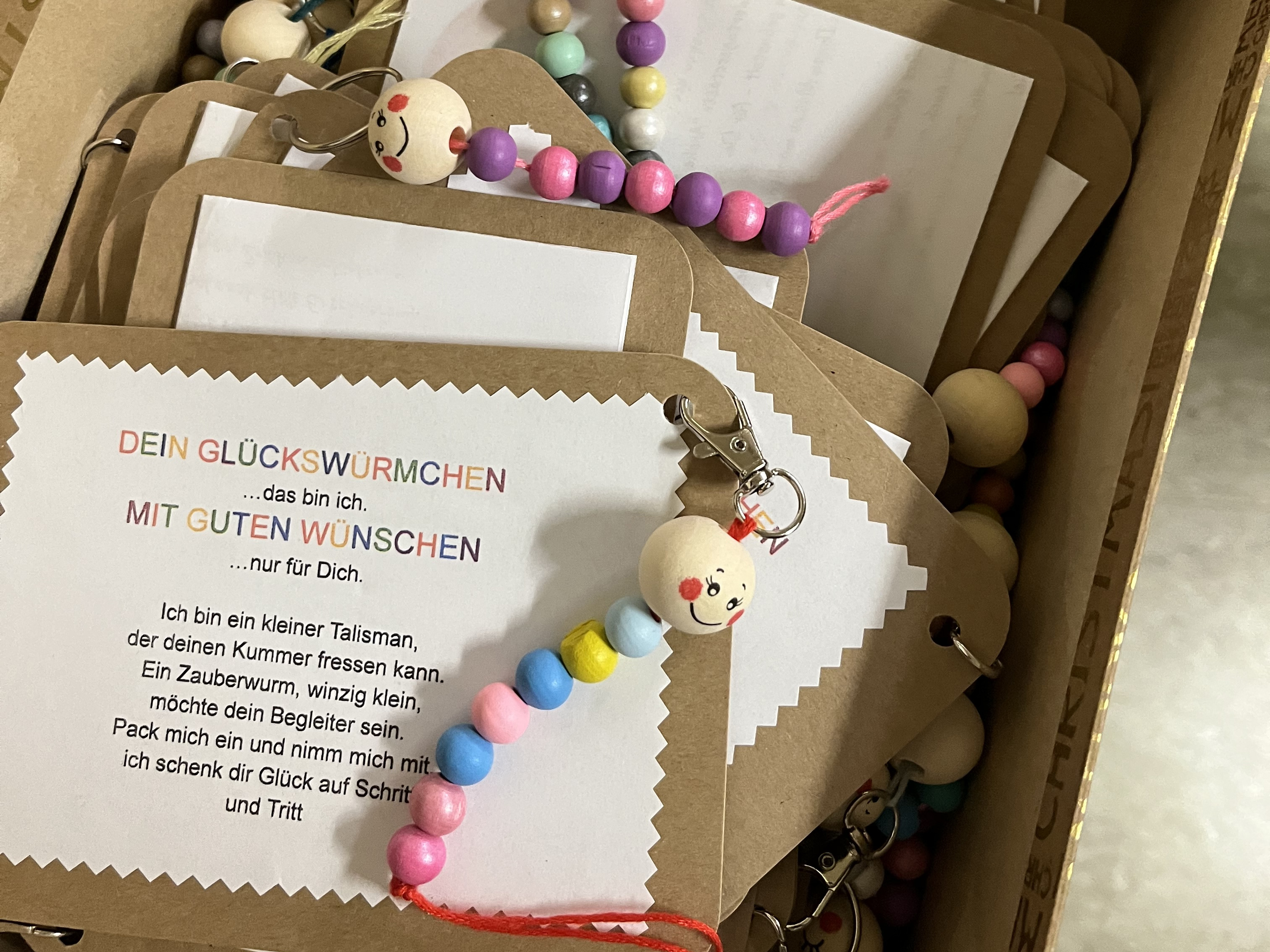 Karton mit selbst gebastelten Glückwürmchen aus bunten Holzperlen