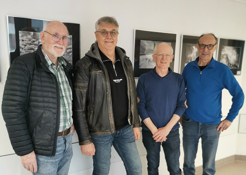Vier Fotografen des Fotoclubs sehen vor ihren Bildern im Krankenhausflur