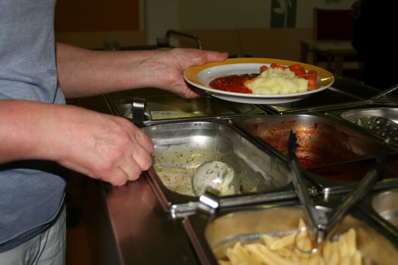 Hauswirtschaftskraft verteilt Essen auf Teller