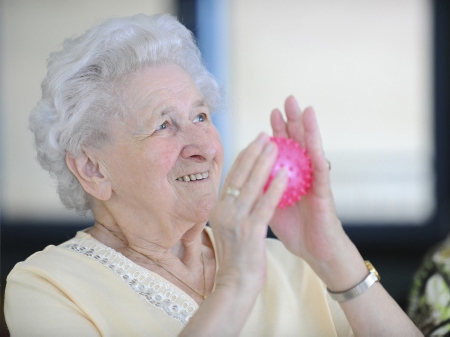 Seniorin bewegt einen Igelball in ihren Händen