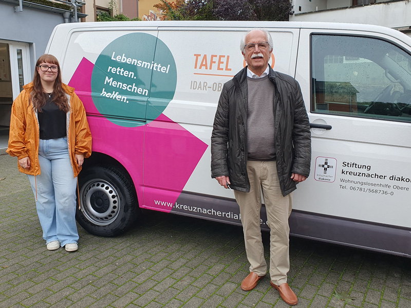 Zwei ehrenamtliche Helfer (eine Frau und ein Mann) stehen vor dem neuen Transporter der Tafel Idar-Oberstein, Wohnungslosenhilfe der Stiftung kreuznacher diakonie