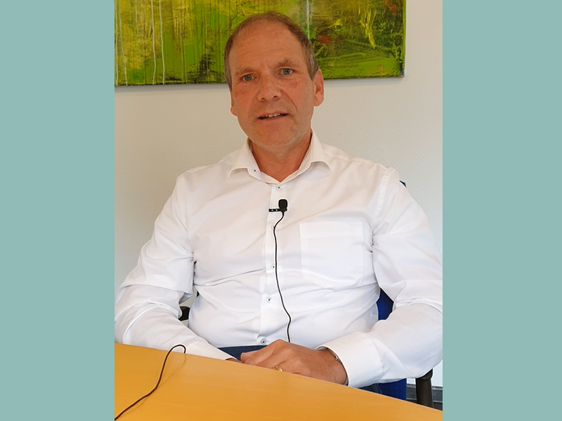 Screenshot eines Videos - Interviewsituation, Mann spricht in Mikro